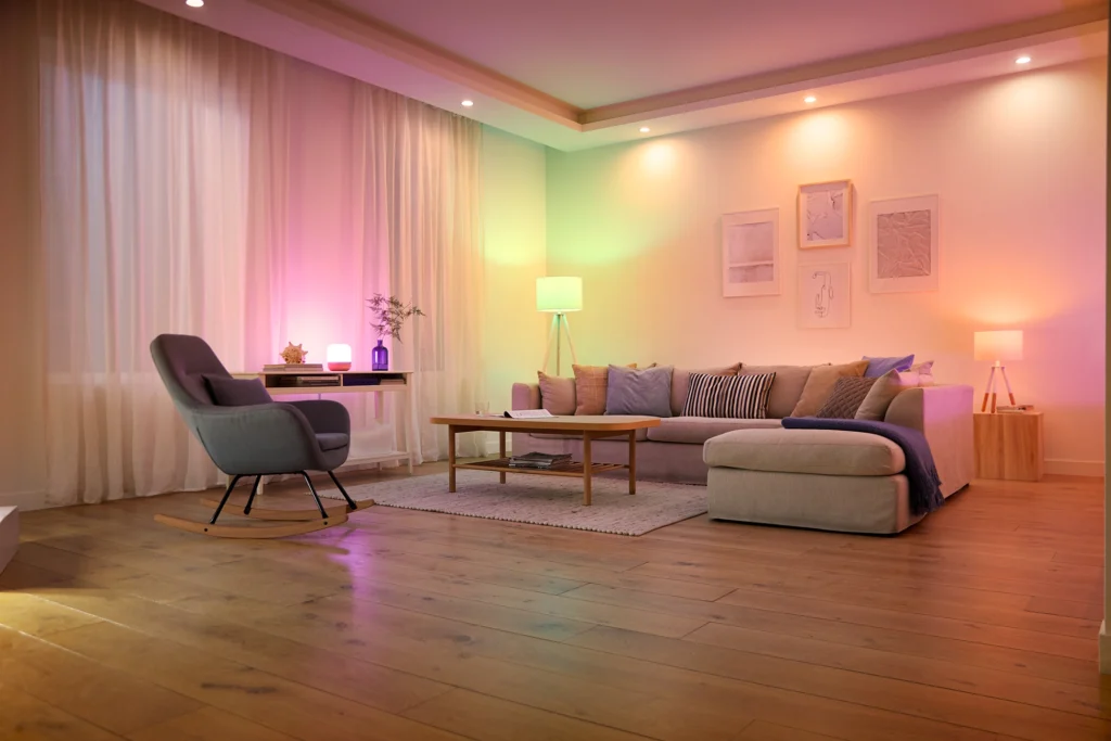 <img src="sala-moderna-iluminacao-colorida.webp" alt="Sala de estar com uma televisão exibindo um fundo marinho colorido, decoração moderna e luzes suaves ao redor.">