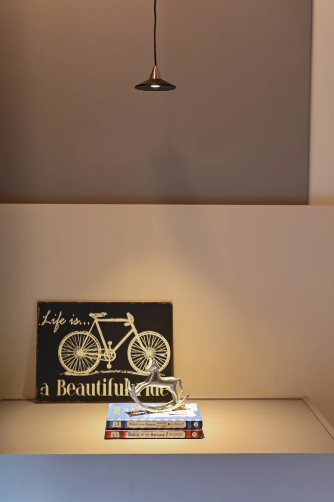 <img src="decoracao-moderna-luminaria-bicicleta-livros.webp" alt="Decoração moderna com luminária pendente, quadro de bicicleta e livros coloridos em uma prateleira, trazendo um toque de estilo e personalidade ao ambiente.">