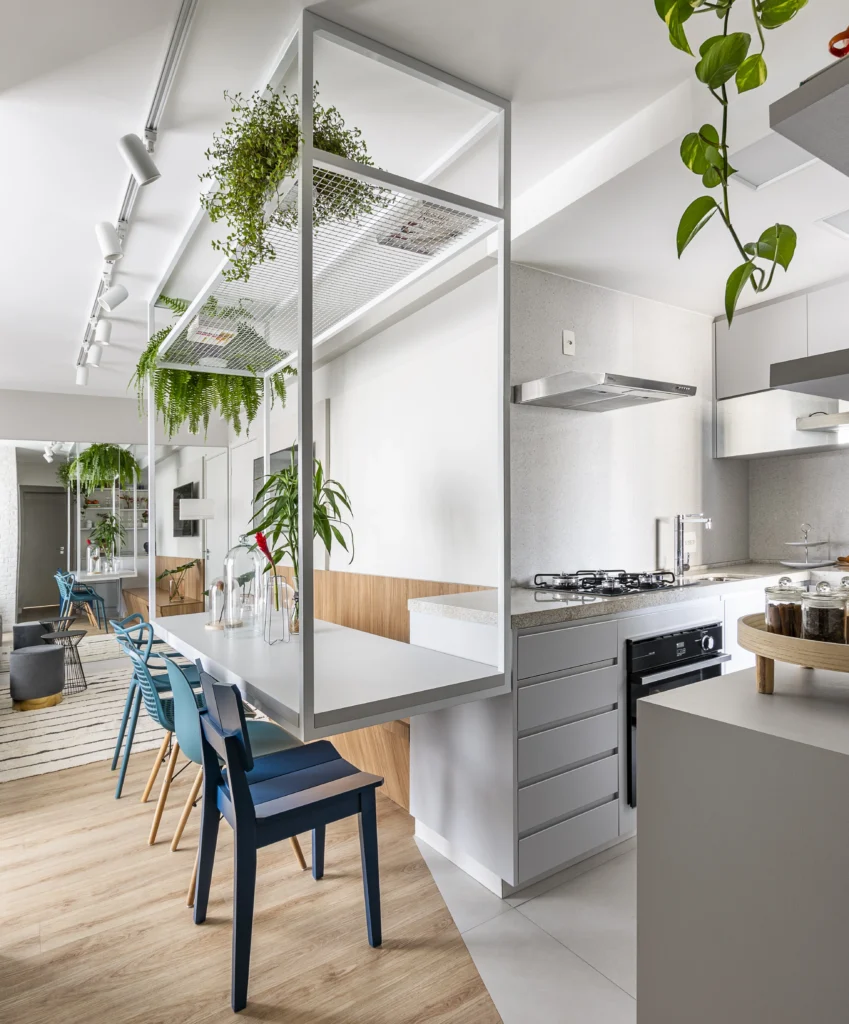 <img src="cozinha-moderna-minimalista-plantas.webp" alt="Cozinha moderna e minimalista com mesas e cadeiras azuis, decoração com plantas pendentes e iluminação contemporânea.">