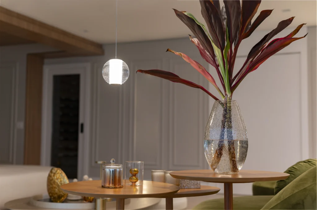 <img src="arranjo-de-plantas-e-decoracao-modernas.webp" alt="Um elegante arranjo de plantas em um vaso de vidro, acompanhado por mesas de madeira e uma luminária moderna, criando uma ambiente acolhedor e sofisticado.">