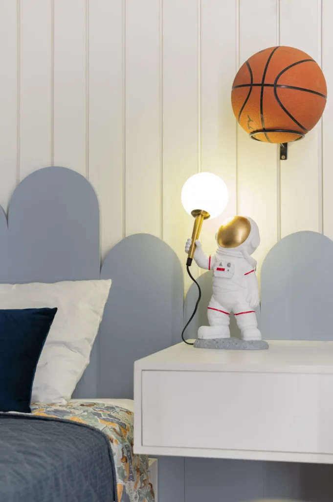 <img src="decoracao-quarto-astronauta-bola-basquete.webp" alt="Decoração moderna de quarto com luminária de astronauta e bola de basquete na parede. Ideal para um ambiente infantil e divertido.">