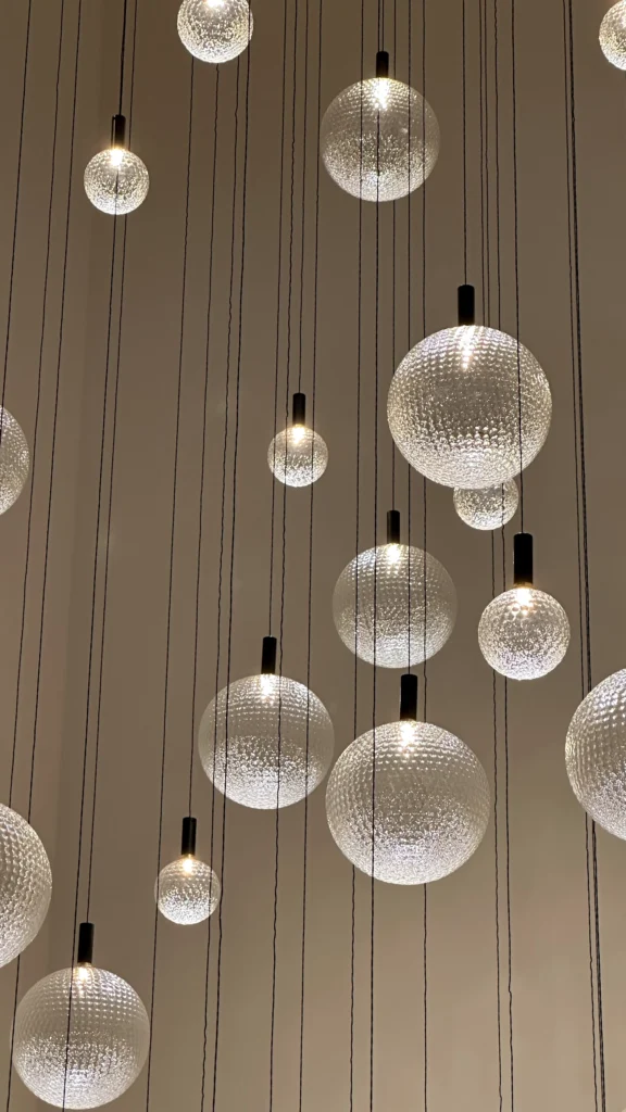 <img src="luminarias-esfera-modernas.webp" alt="Luminárias modernas em formato de esfera, penduradas por fios finos, criando um efeito iluminado e contemporâneo em decoração.">