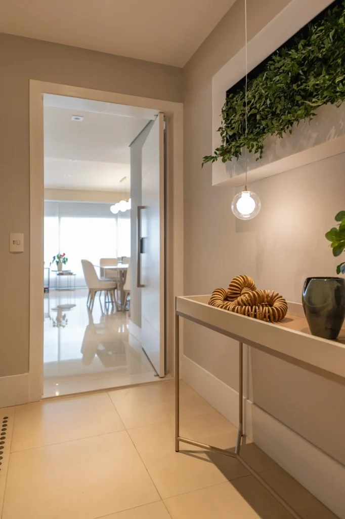 <img src="entrada-apartamento-moderno.webp" alt="Entrada de apartamento moderno com mesa decorativa, iluminação pendente e planta, oferecendo elegância e aconchego ao ambiente. Ideal para decoração de interiores.">