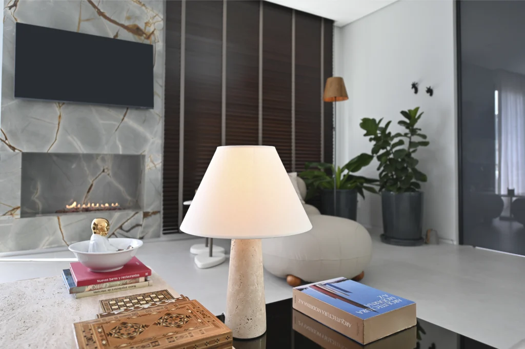 <img src="sala-de-estar-moderno-elegante.webp" alt="Sala de estar moderna com decoração elegante e aconchegante, destaque para luminária de mesa, plantas, lareira de mármore e televisão na parede.">