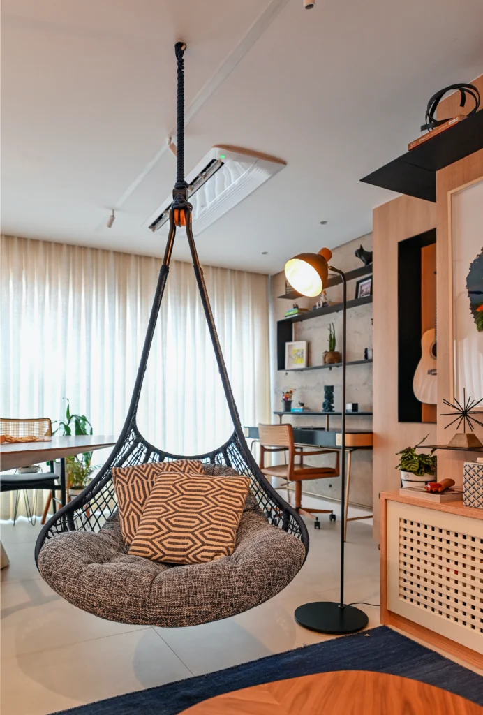 <img src="sala-de-estar-moderno-com-cadeira-pendurada-e-estantes.webp" alt="Sala de estar moderna com cadeira de balanço pendurada, mesa de estudos, estantes decoradas e iluminação aconchegante, ideal para conforto e decoração de interiores.">