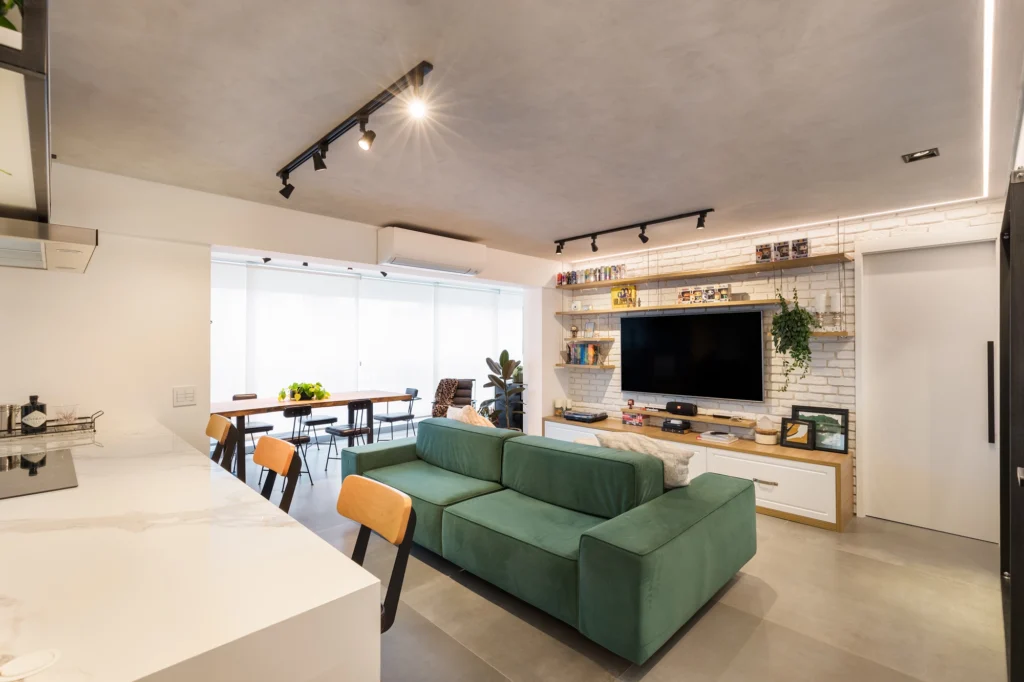 <img src="sala-de-estar-moderno-e-espacosa-com-televisao-e-sofa-verde.webp" alt="Sala de estar moderna e espaçosa com sofá verde, televisão de tela plana, prateleiras decorativas, iluminação embutida e ambiente bem iluminado.">