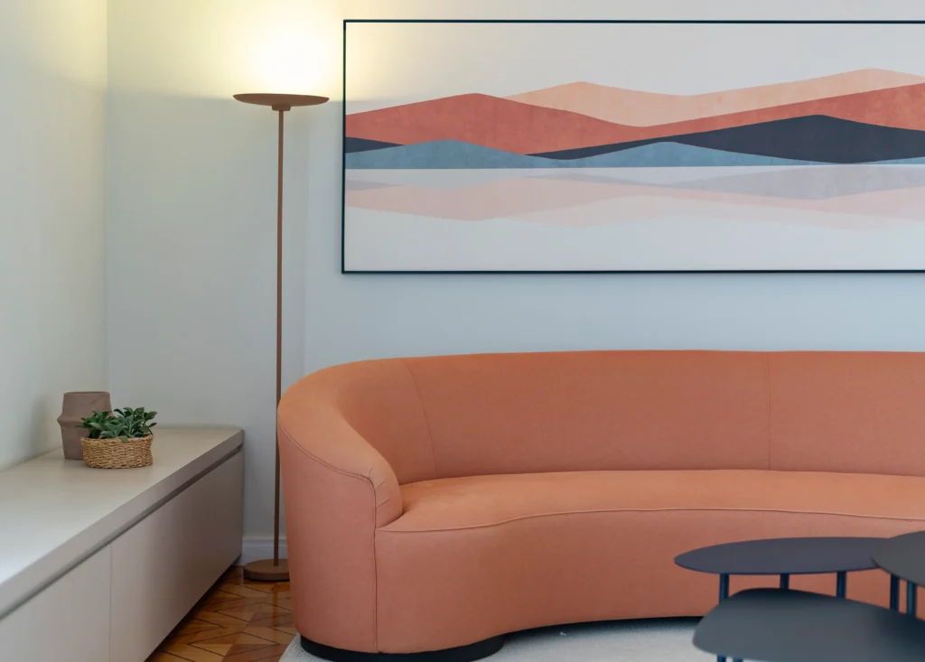 <img src="sala-ambiente-moderno-sofa-rosa-parede-arte-abstrata.webp" alt="Sala de estar moderna com sofá rosa claro, iluminação suave, pintura abstrata nas cores azul, rosa e marrom, e uma luminária de pé no canto">