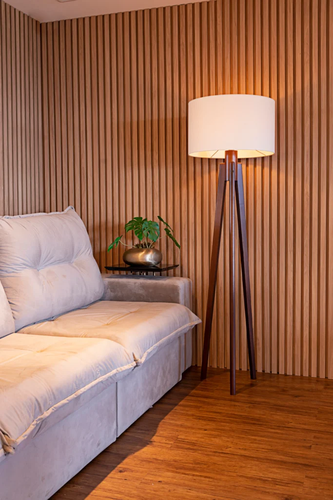 <img src="sala-de-estar-moderno-com-sofa-branco-e-luminaria-de-madeira.webp" alt="Sala de estar moderna com sofá branco, luminária de piso de madeira e parede de lamas de madeira decorativa, criando ambiente aconchegante e elegante.">