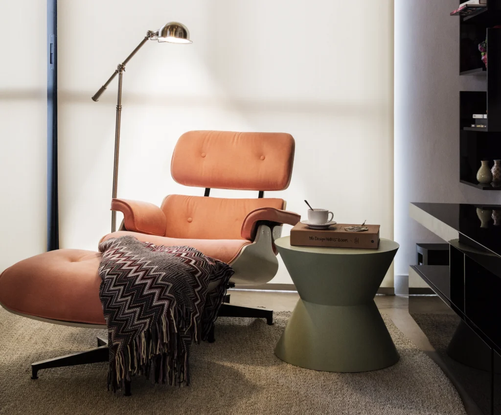 <img src="sofa-de-design-moderno-cor-rosa-claro-sala-de-estar.webpg" alt="Sofá de design moderno em cor rosa claro, com uma manta de tricô sobre o assento, ao lado de uma mesa de apoio com uma xícara e um livro, em um ambiente aconchegante de sala de estar.">