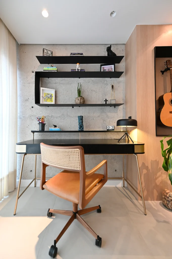 <img src="home-office-moderna-design-resultado.webp" alt="Home office com mesa preta, cadeira de madeira com rodízios, prateleiras pretas na parede de cimento ao fundo, decoração moderna com livros, plantas e objetos de arte.">
