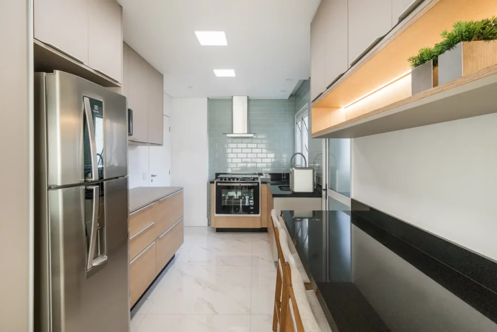 <img src="cozinha-moderna-2023-jpg.webp" alt="Cozinha moderna com eletrodomésticos de aço inox, armários claros, bancada preta e detalhes de plantas na prateleira, ideal para decoração de ambientes contemporâneos.">