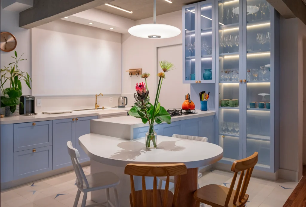 <img src="cozinha-moderno-armarios-azuis-mesa-flores.webp" alt="Cozinha moderna com armários azuis, mesa de jantar com vaso de flores e iluminação suave, ideal para ambientes de convivência e preparo de refeições.">