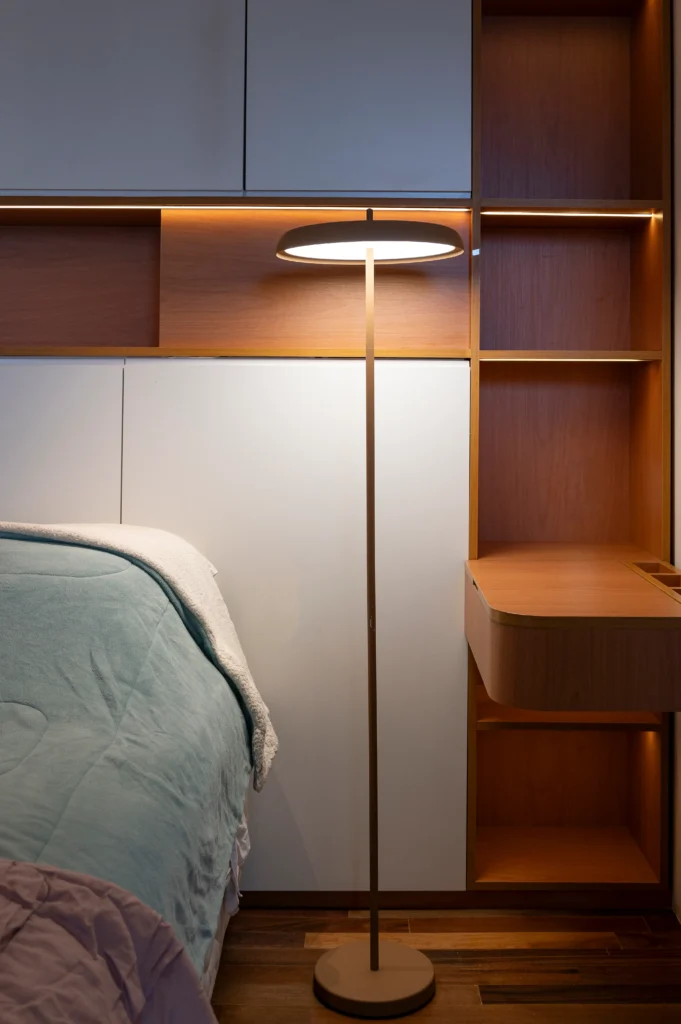 <img src="luminaria-de-piso-moderna-quarto-decoracao-minimalista.webp" alt="Luminária de piso moderna com iluminação suave ao lado de uma cama, em um quarto com decoração minimalista e painéis de madeira e cores neutras.">