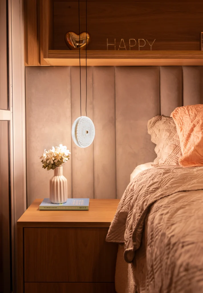 <img src="quartoaconchegantedecoracaohappy-jpg.webp" alt="Quarto aconchegante com luminária moderna, vaso de flores na mesinha de cabeceira e decoração de parede com a palavra 'HAPPY' em destaque.">