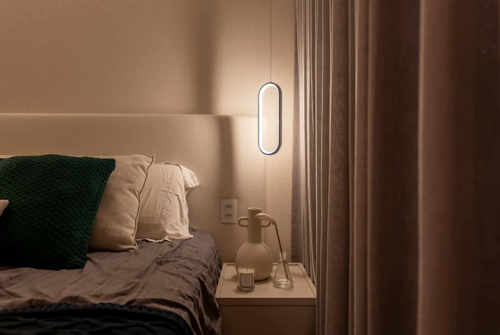 <img src="quartoaconcheganteiluminacaosuave.webp" alt="Imagem de um quarto aconchegante com iluminação suave ao lado da cama, com travesseiros grandes e um criado-mudo com objeto decorativo ao lado, perfeito para relaxar e dormir bem.">