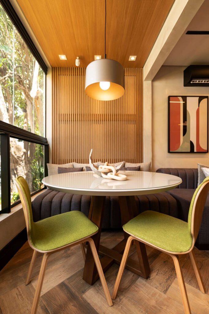 Mesa retangular com cadeiras dispostas ao redor, decorada de forma elegante, destacando o pendente metálico como elemento central na decoração